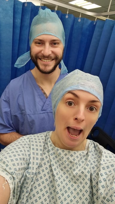 Alice and her partner Connor wearing surgical caps and scrubs, smiling together at Care Fertility Leeds before fertility treatment.