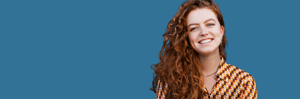 A single woman with curly ginger hair smiling.