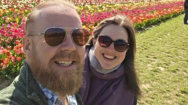 Heather and David smiling together in a colourful tulip field before starting their family.