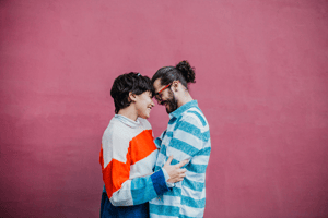 Man and woman hugging pink background