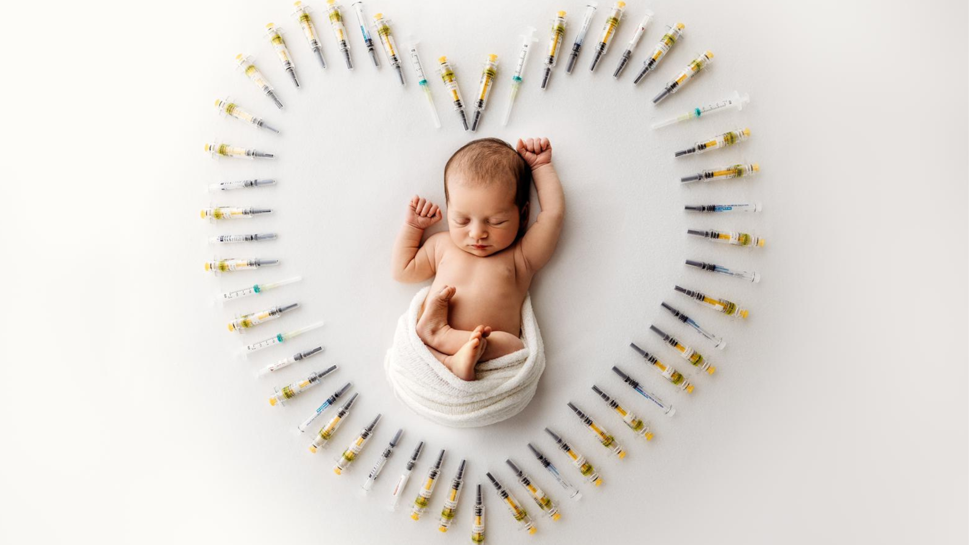 Newborn baby of Charlie and Tom lies peacefully surrounded by IVF medication needles arranged in a heart shape. After their fertility journey with Care Fertility Tamworth, shared on TikTok @griggsjourneyto3.