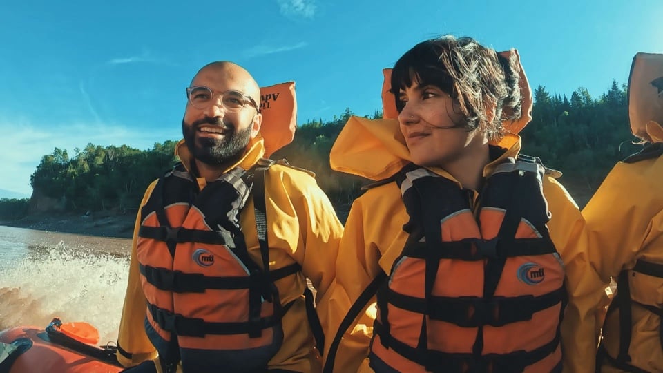 Zainib and Mobeen wearing life jackets on a boat during Race Across the World, smiling at each other.